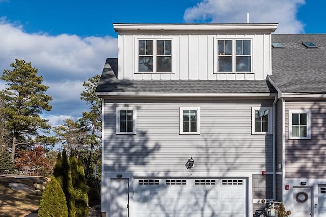 view of property exterior with an attached garage, board and batten siding, and roof with shingles