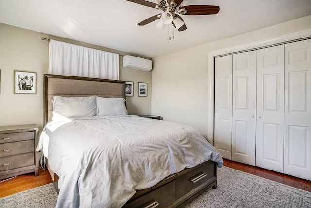 bedroom with ceiling fan, a closet, light wood-type flooring, and a wall unit AC