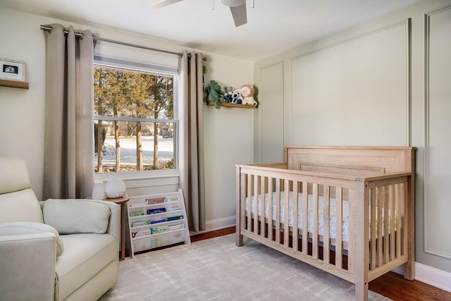 bedroom with ceiling fan, a crib, multiple windows, and light hardwood / wood-style flooring