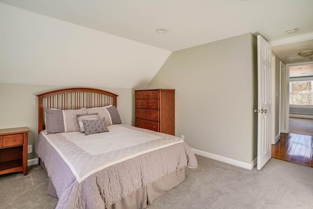 carpeted bedroom with baseboard heating and vaulted ceiling