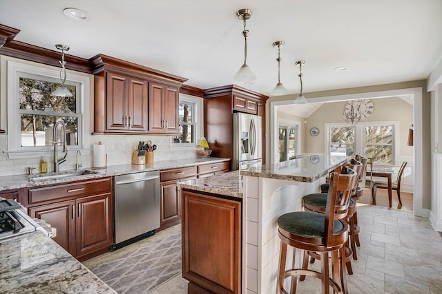 kitchen with a kitchen island, stainless steel appliances, sink, hanging light fixtures, and a kitchen breakfast bar