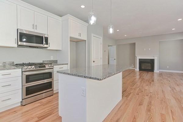 kitchen with white cabinets, a kitchen island, stainless steel appliances, hanging light fixtures, and light hardwood / wood-style flooring