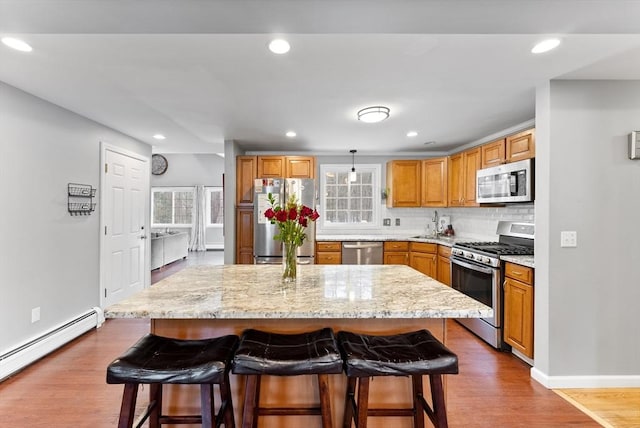 kitchen with stainless steel appliances, a center island, hanging light fixtures, and a breakfast bar