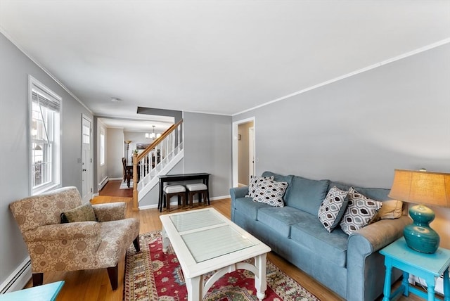 living area featuring a baseboard heating unit, a chandelier, wood finished floors, and ornamental molding