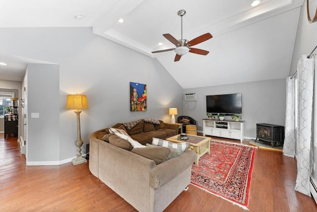 living area with wood finished floors, a ceiling fan, baseboards, an AC wall unit, and a wood stove