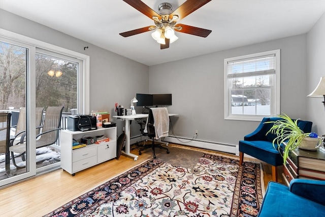 office space featuring a baseboard heating unit, ceiling fan, and wood finished floors