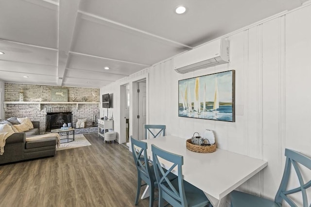 dining room with an AC wall unit, wood finished floors, brick wall, recessed lighting, and beamed ceiling