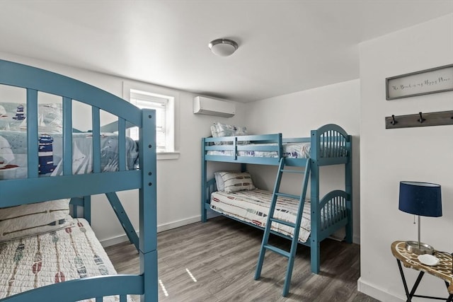 bedroom featuring wood finished floors, a wall mounted air conditioner, and baseboards