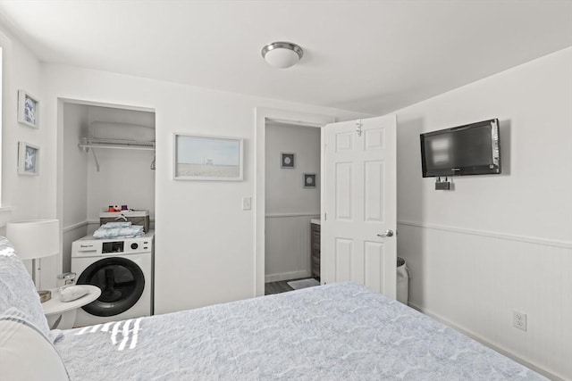 bedroom featuring washer / clothes dryer, wainscoting, and a closet