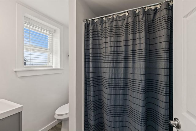 bathroom with toilet, baseboards, curtained shower, wood finished floors, and vanity