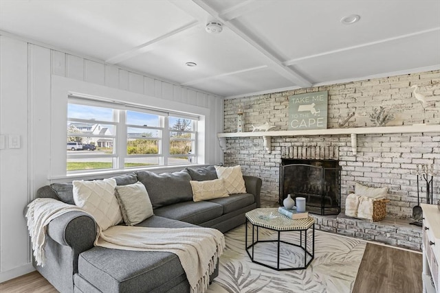 living room with wood finished floors, brick wall, beamed ceiling, and a fireplace