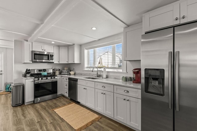 kitchen with appliances with stainless steel finishes, a sink, dark wood-style flooring, beamed ceiling, and recessed lighting