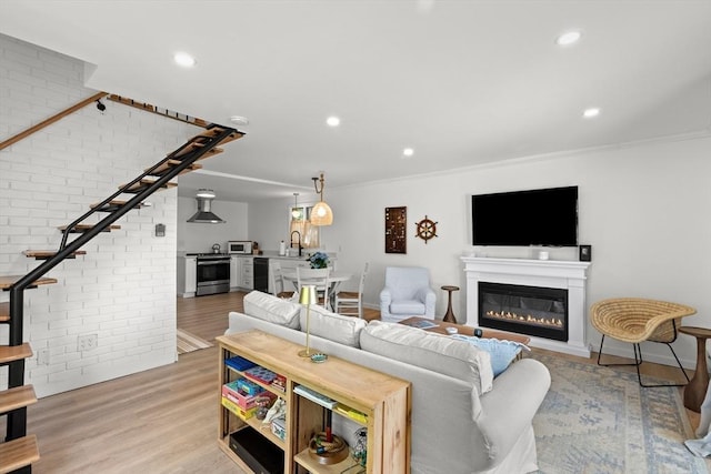 4 Agawam Ave, Ipswich, MA 01938 - living area with wood finished floors, a glass covered fireplace, crown molding, brick wall, and recessed lighting