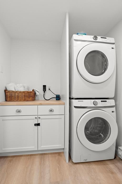 4 Agawam Ave, Ipswich, MA 01938 - laundry room featuring stacked washer / drying machine, cabinet space, and light wood-type flooring