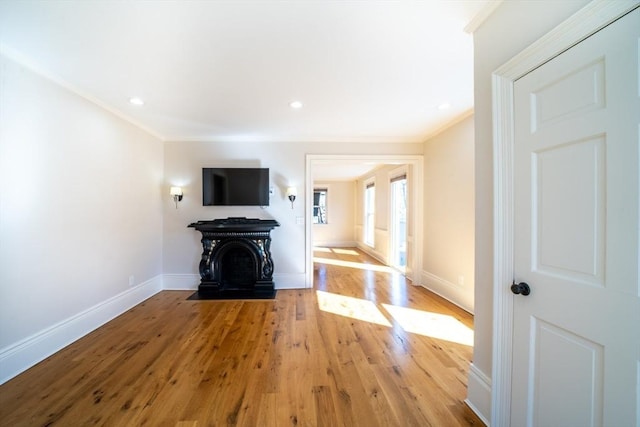 unfurnished living room featuring ornamental molding, light wood-type flooring, and baseboards