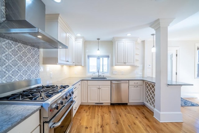 kitchen with stainless steel appliances, light wood-type flooring, a sink, and wall chimney range hood