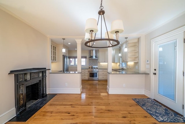 kitchen featuring wood finished floors, a sink, wall chimney range hood, appliances with stainless steel finishes, and open shelves