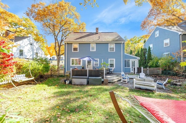 back of property with a deck and a lawn