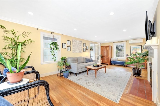 living room featuring french doors, ornamental molding, an AC wall unit, and light wood-type flooring