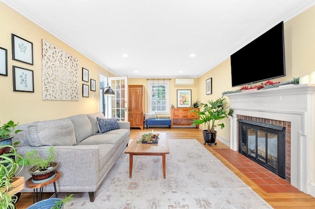 living room featuring ornamental molding, an AC wall unit, a fireplace, and light wood-type flooring