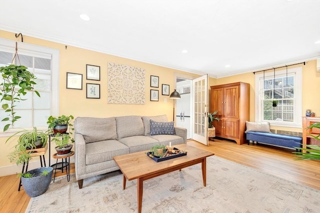 living room with ornamental molding, french doors, and light wood-type flooring