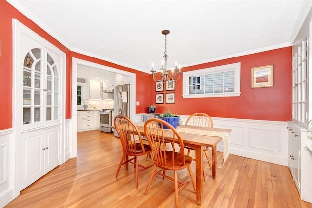 dining space featuring a notable chandelier, light hardwood / wood-style flooring, and ornamental molding