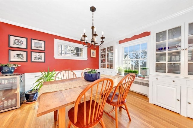 dining space featuring an inviting chandelier, ornamental molding, radiator heating unit, and light wood-type flooring