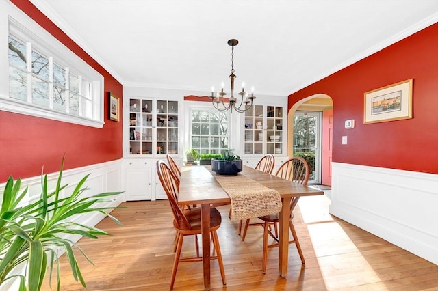 dining room with an inviting chandelier, crown molding, and light wood-type flooring