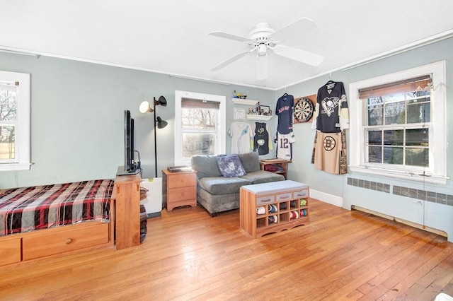 living room featuring radiator, crown molding, light hardwood / wood-style floors, and ceiling fan