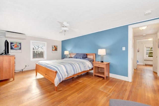 bedroom with ceiling fan, a wall mounted air conditioner, light hardwood / wood-style flooring, and radiator heating unit