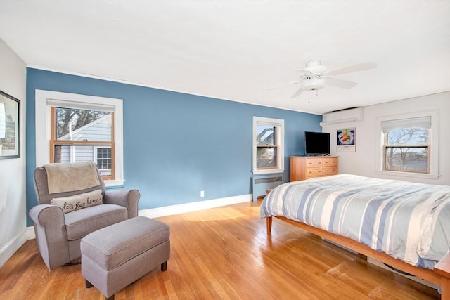 bedroom with radiator heating unit, light hardwood / wood-style floors, and multiple windows