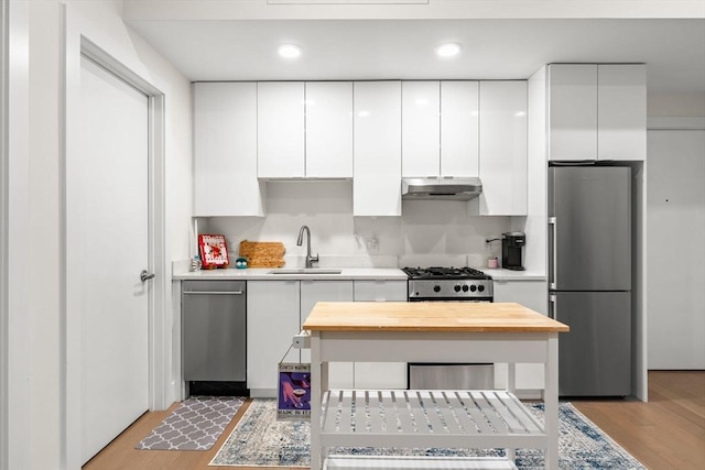 121 Portland St Unit 505, Boston, MA 02114 - kitchen with stainless steel appliances, under cabinet range hood, white cabinetry, light wood-style floors, and recessed lighting