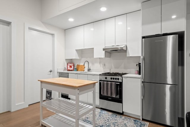 121 Portland St Unit 505, Boston, MA 02114 - kitchen with appliances with stainless steel finishes, under cabinet range hood, light countertops, white cabinetry, and modern cabinets