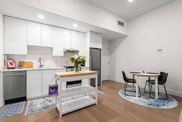 121 Portland St Unit 505, Boston, MA 02114 - kitchen featuring stainless steel appliances, light wood-style flooring, white cabinets, under cabinet range hood, and recessed lighting