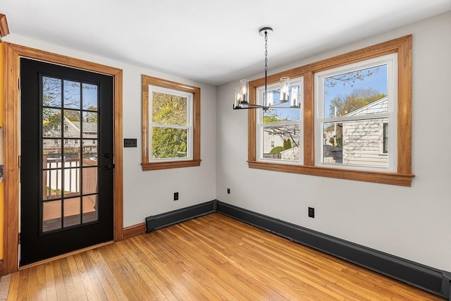 unfurnished dining area featuring baseboards, a notable chandelier, and light wood-style floors
