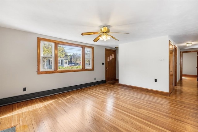 empty room featuring ceiling fan, visible vents, baseboards, and light wood finished floors