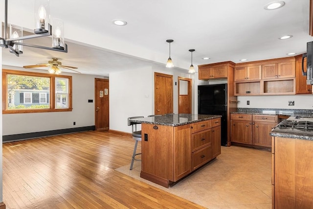 kitchen with a ceiling fan, a center island, open shelves, brown cabinets, and freestanding refrigerator