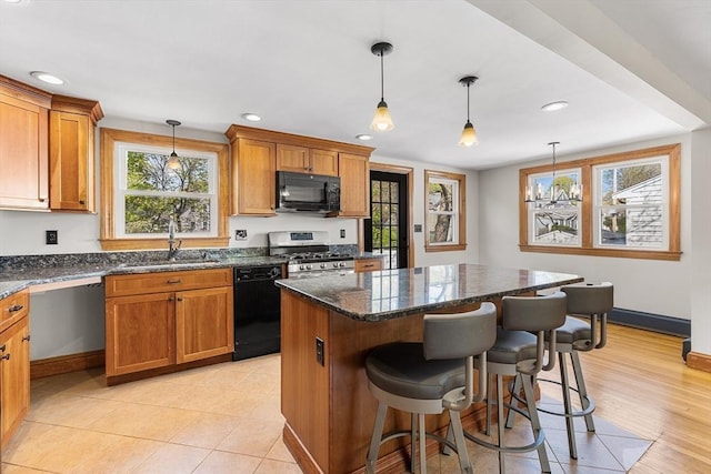 kitchen featuring brown cabinetry, a center island, a sink, black appliances, and recessed lighting