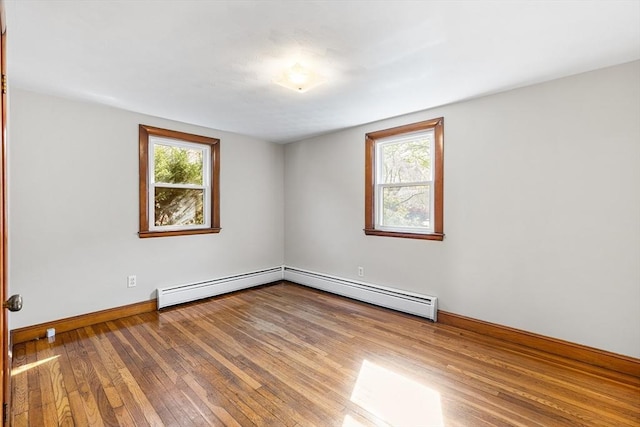 empty room with wood-type flooring, baseboards, a baseboard heating unit, and baseboard heating