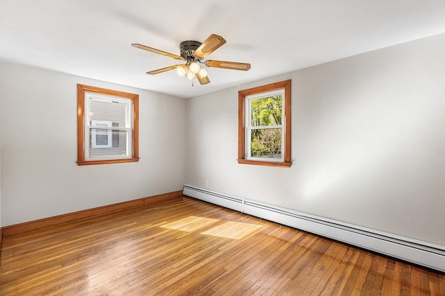 empty room featuring baseboards, ceiling fan, a baseboard heating unit, and light wood-style flooring