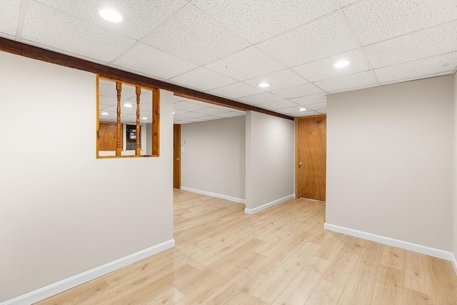 finished below grade area with a paneled ceiling, recessed lighting, baseboards, and wood finished floors