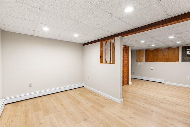 finished below grade area featuring baseboards, baseboard heating, and wood finished floors