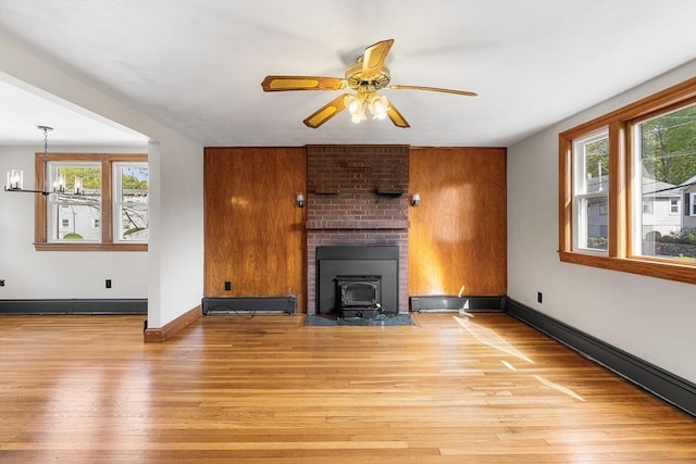 unfurnished living room featuring plenty of natural light, light wood finished floors, and a baseboard radiator
