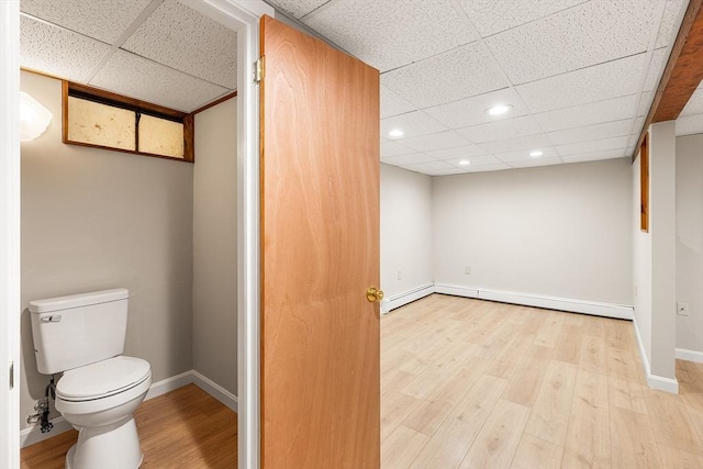 bathroom with toilet, a paneled ceiling, recessed lighting, baseboards, and wood finished floors