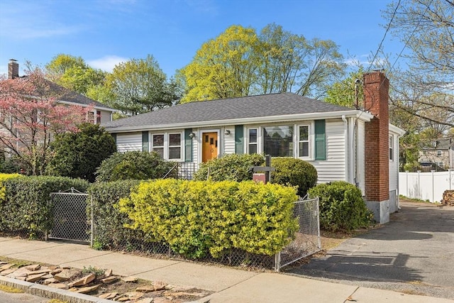 view of front of property featuring fence, a chimney, and roof with shingles