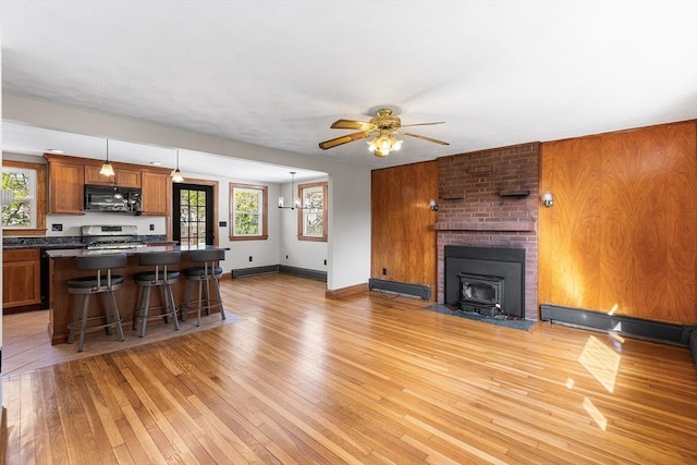 kitchen with black microwave, dark countertops, light wood-style floors, stainless steel range with gas cooktop, and brown cabinets