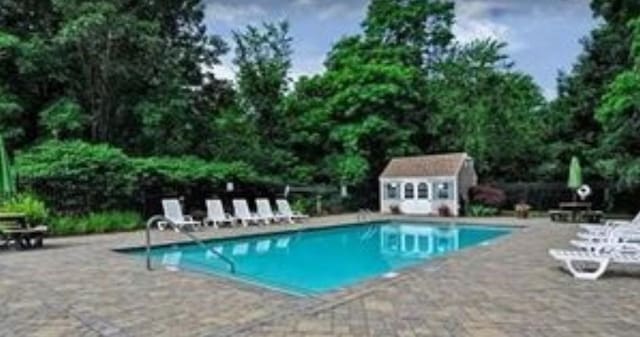 community pool with a patio area and an outbuilding