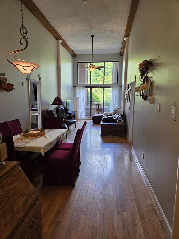 dining area featuring wood-type flooring, a textured ceiling, and baseboards