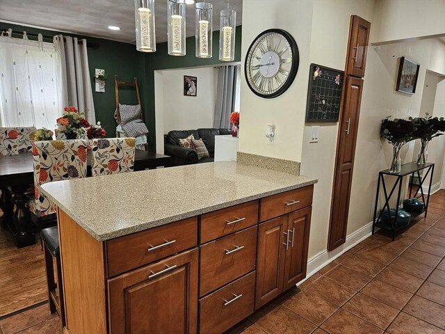 16 Boyd Ave, East Providence, RI 02914 - kitchen with dark tile patterned flooring, open floor plan, light stone countertops, brown cabinets, and baseboards