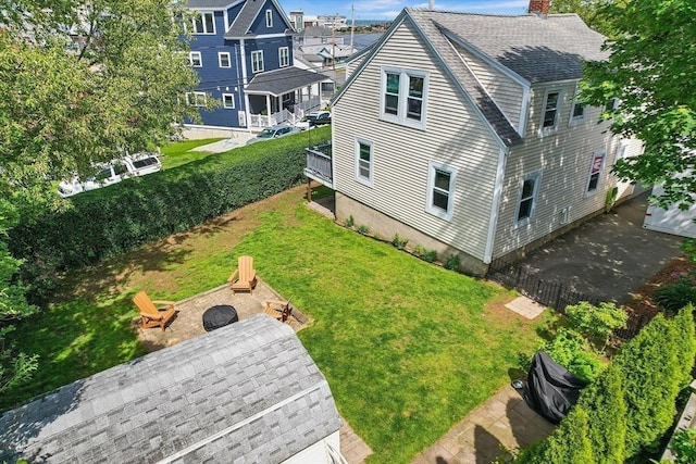 134 Hampton Cir, Hull, MA 02045 - back of property with a fire pit, a chimney, roof with shingles, and a lawn